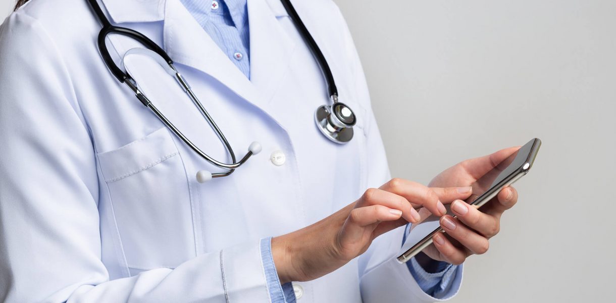 unrecognizable-doctor-using-smartphone-on-white-st-DLKHN8M
